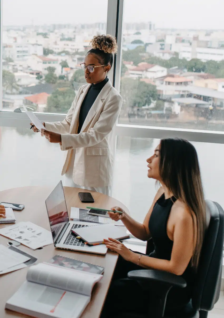 Two professionals collaborating in a modern office with laptops and documents.